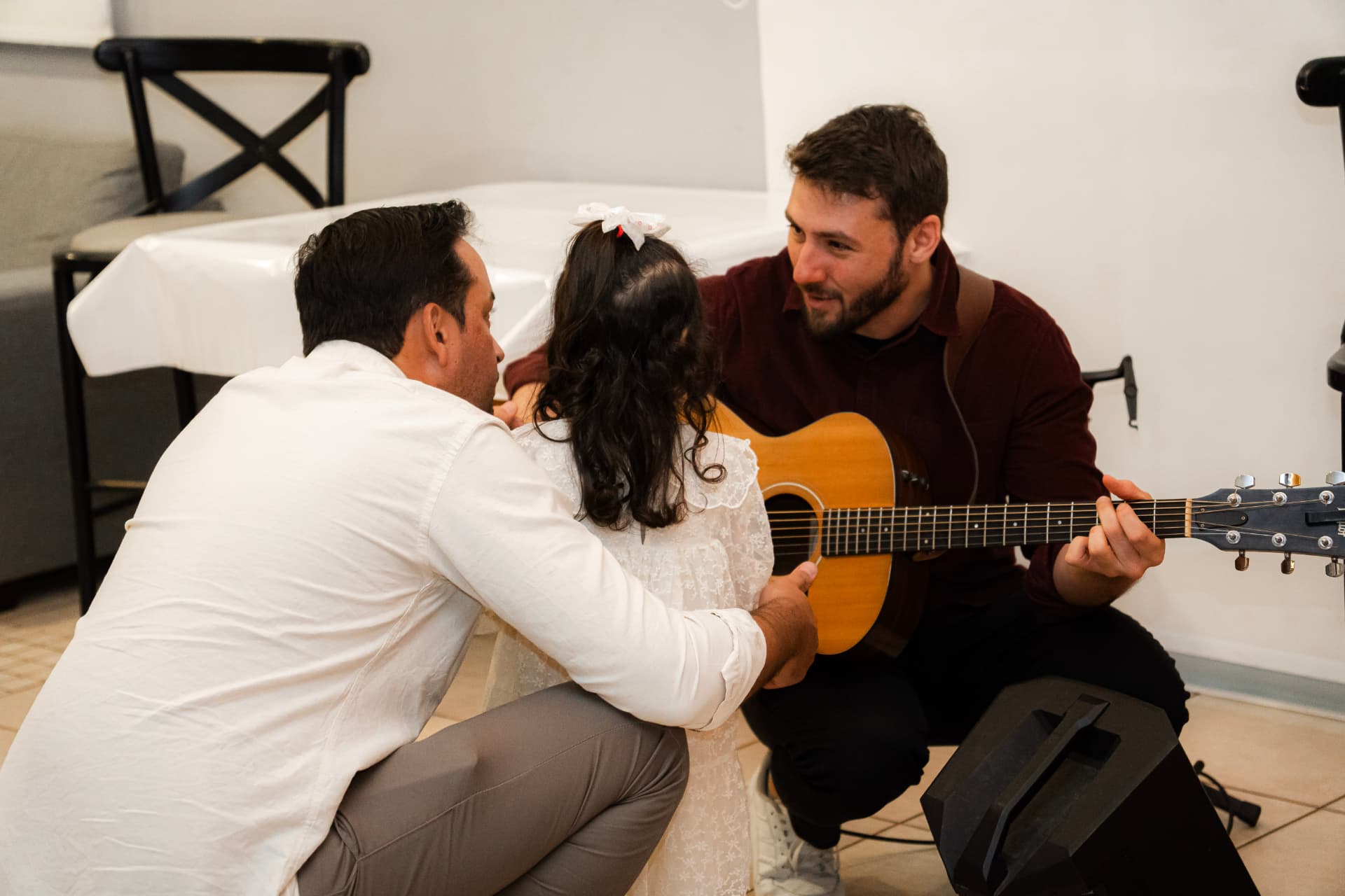 Roger Loeblein ao violão interagindo com uma criança e sua família em uma celebração